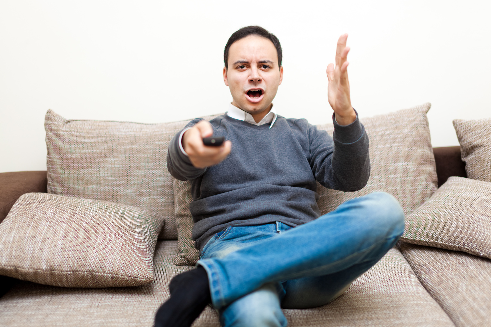 Angry man watching TV on his sofa